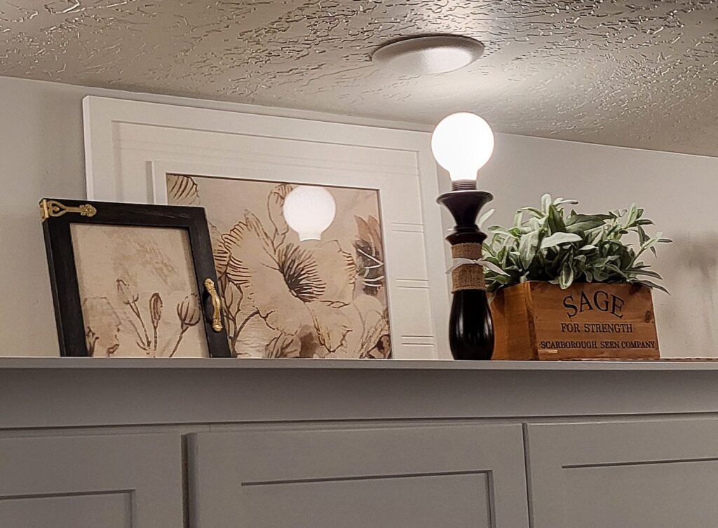 Throw pillow case repurposed as art in these thrifted frames. Grouped with one lamp and a wooden box of herbs